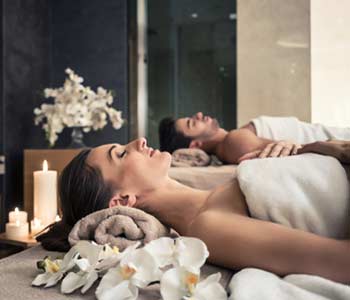 Young man and woman lying down on massage beds at luxury spa and wellness center